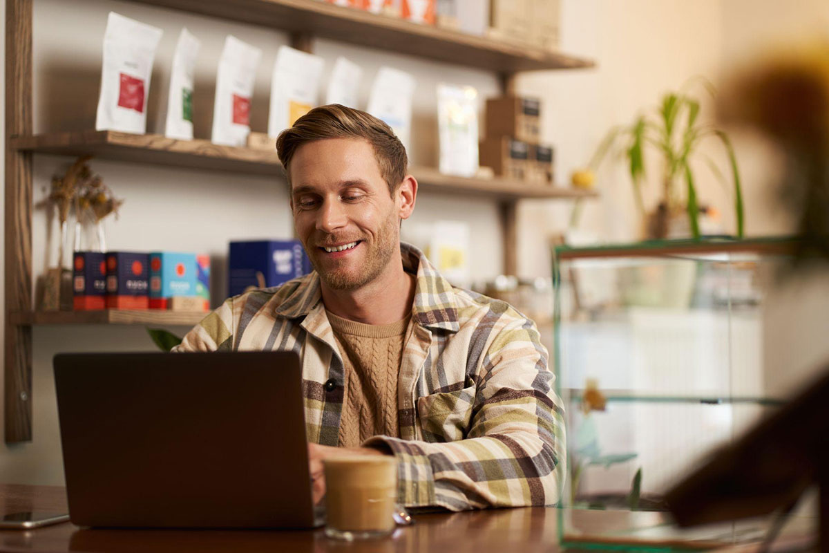 young man sitting at the coffee shop with a laptop